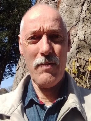 Man with mustache outdoors, wearing a denim shirt and jacket