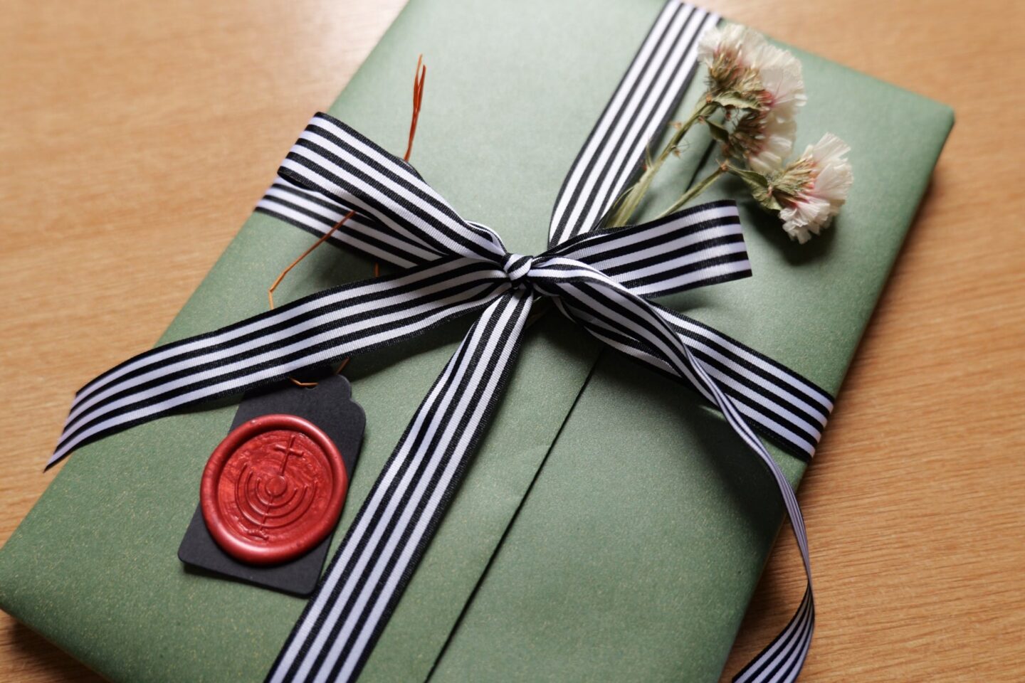 Green gift box with black and white striped ribbon and red wax seal