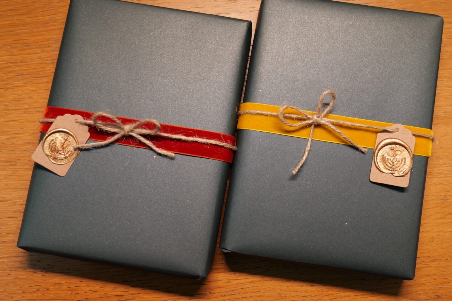Two dark gray wrapped gifts with velvet ribbons and wax seals