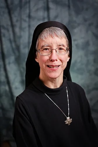 Sister Mary Catherine, a Catholic nun with glasses and a wimple, smiles warmly