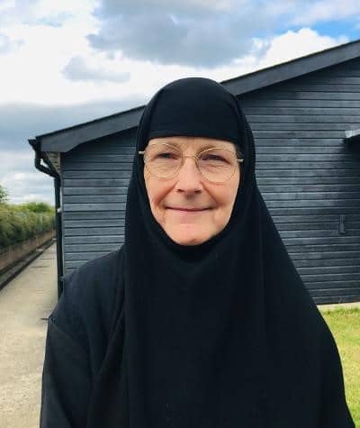 Woman in black hijab and glasses outside a dark building