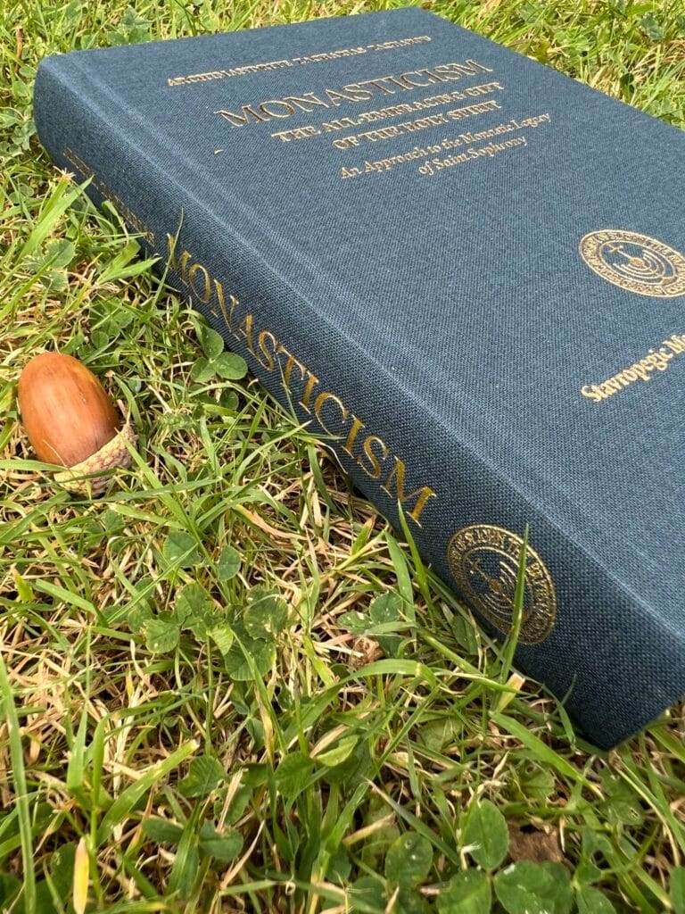 Monasticism book resting on grass next to an acorn.