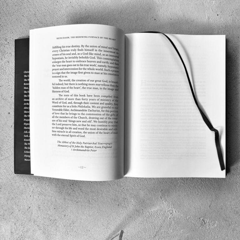 Open book with text and a black ribbon bookmark, showing page 12