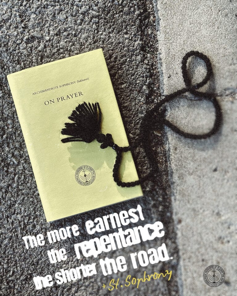 Book "On Prayer" by Archimandrite Sophrony with prayer beads on asphalt