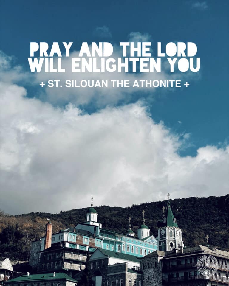 Monastery buildings on a mountainside under a cloudy sky with text: "PRAY AND THE LORD WILL ENLIGHTEN YOU + ST. SILOUAN THE ATHONITE +