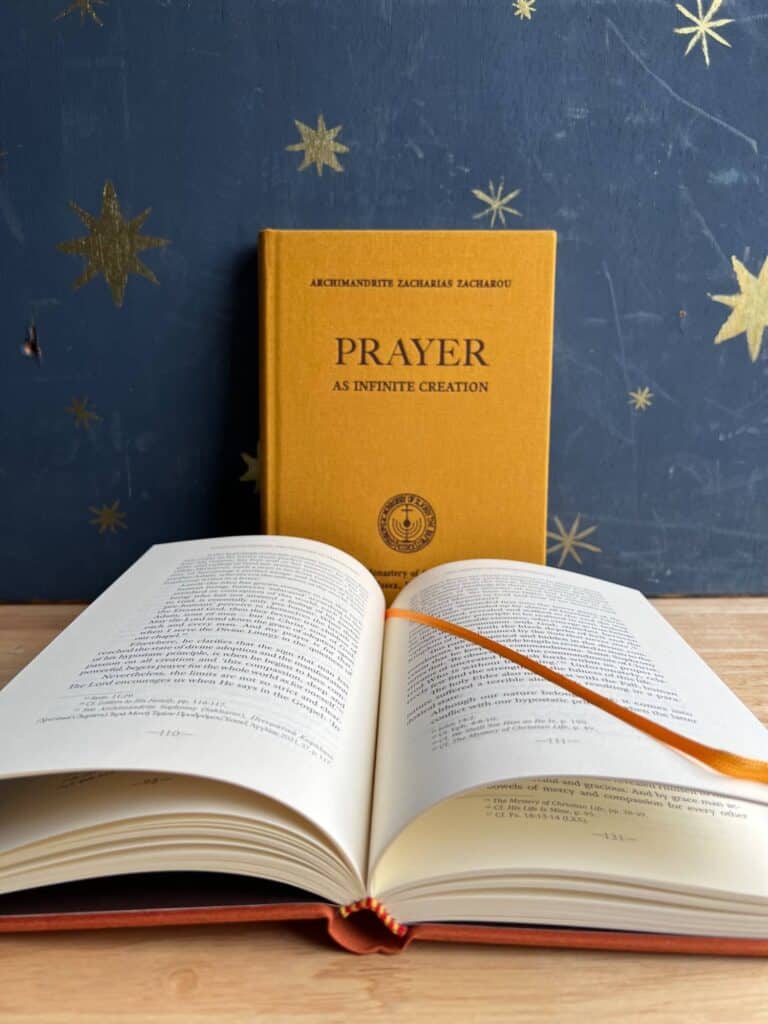 Open book with "Prayer: As Infinite Creation" by Archimandrite Zacharias Zacharou