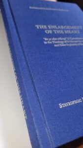 The Enlargement of the Heart book cover with gold text on blue fabric.
